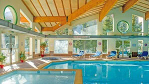An indoor swimming pool with wooden beams, sunlit rooms, and lounge chairs. - Club Les Alpes Dazur (La Salle-les-Alpes)