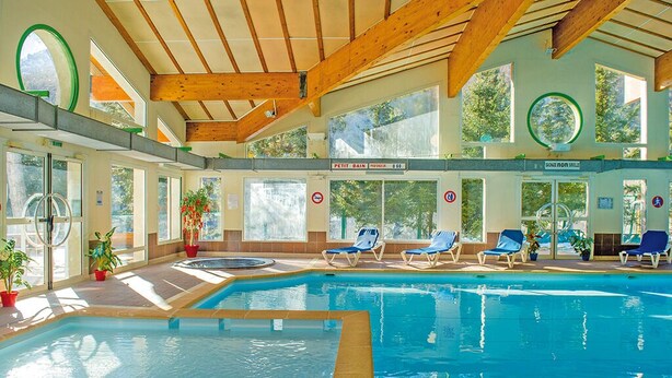 An indoor swimming pool with wooden beams, sunlit rooms, and lounge chairs. - Club Les Alpes Dazur (La Salle-les-Alpes)