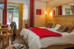 Ein Schlafzimmer mit einem Bett, einem Schreibtisch mit einem Laptop, einer Lampe und einem Fenster mit Vorhängen.