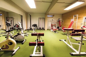 Une salle de sport équipée de divers appareils d’exercice, notamment des tapis de course, des vélos d’appartement et des appareils de musculation.