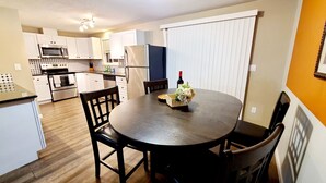 A modern kitchen with white cabinets, stainless steel appliances, and a dining table with chairs. - 2 Levels 2 Bedrooms with Office Spaces (Beaverton)