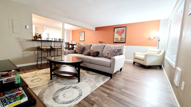 A living room with a sofa, coffee table, and chairs. There is a dining area with a table and chairs in the background. - 2 Levels 2 Bedrooms with Office Spaces (Beaverton)