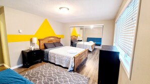 A bedroom with two beds, a mirror, a wardrobe, and a bedside table. - 2 Levels 2 Bedrooms with Office Spaces (Beaverton)