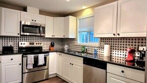 A modern kitchen with white cabinets, stainless steel appliances, and a patterned backsplash. - 2 Levels 2 Bedrooms with Office Spaces (Beaverton)