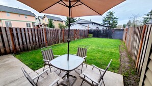 A patio with a table and chairs, a wooden fence, and houses in the background. - 2 Levels 2 Bedrooms with Office Spaces (Beaverton)
