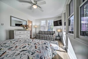 A bedroom with a bed, a sofa, a ceiling fan, a TV, and large windows. - Sapphire Home w/ Grill & Pool Access (Sapphire)