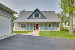 Une maison à deux étages avec un porche à l’avant, un garage et une pelouse bien entretenue.