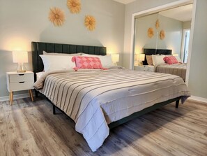 Une chambre à coucher avec un lit, des tables de chevet et un miroir.