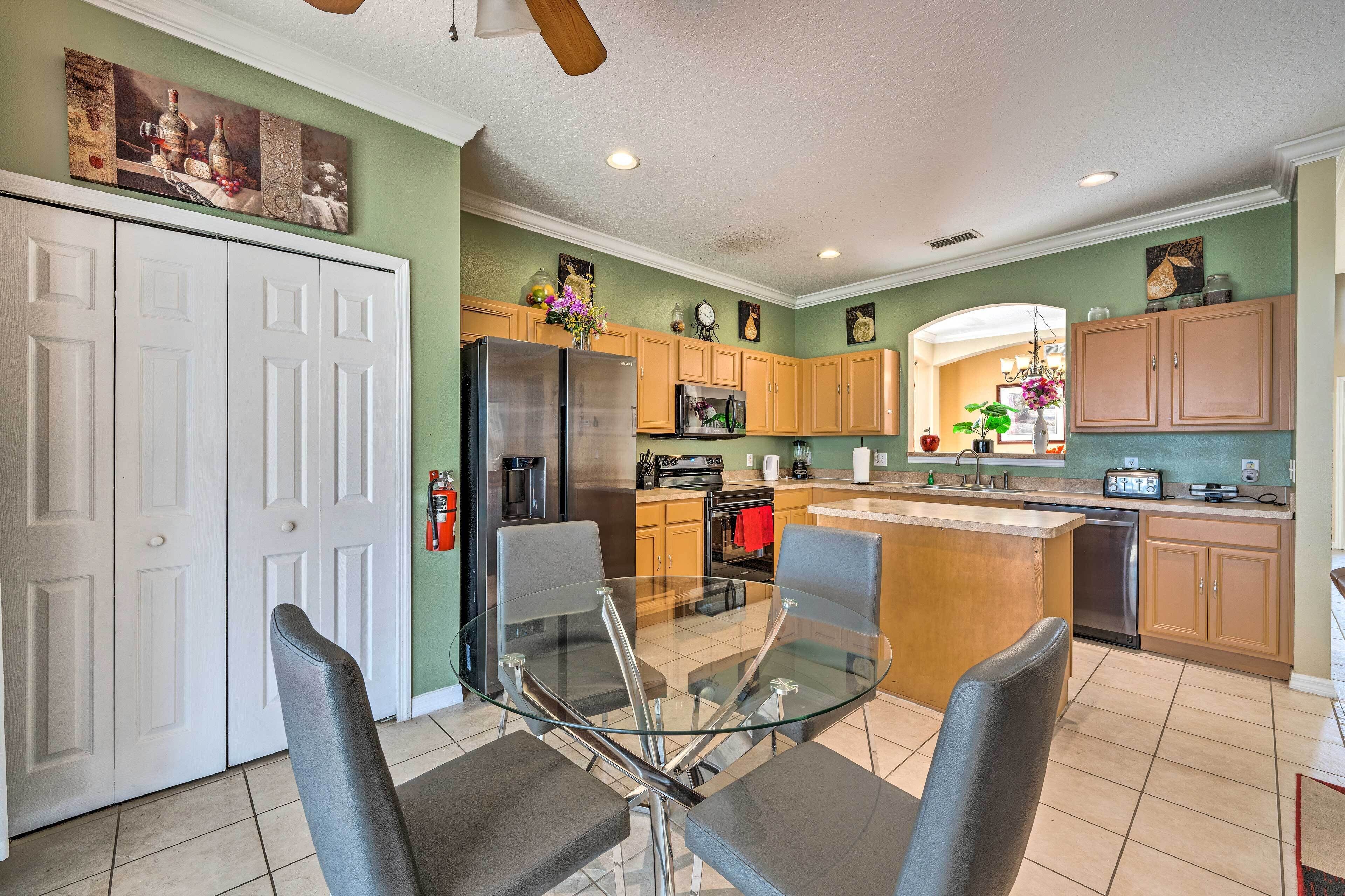 A modern kitchen with a glass dining table, wooden cabinets, and stainless steel appliances.