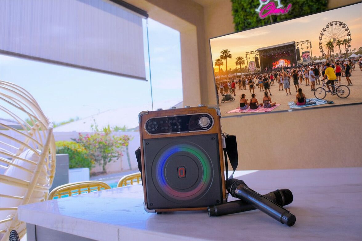 A camera with a microphone on a table, a poster of a crowded event, and a chair.