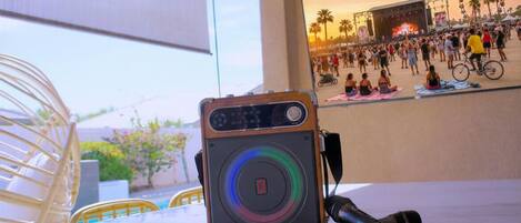 A camera with a microphone on a table, a poster of a crowded event, and a chair.