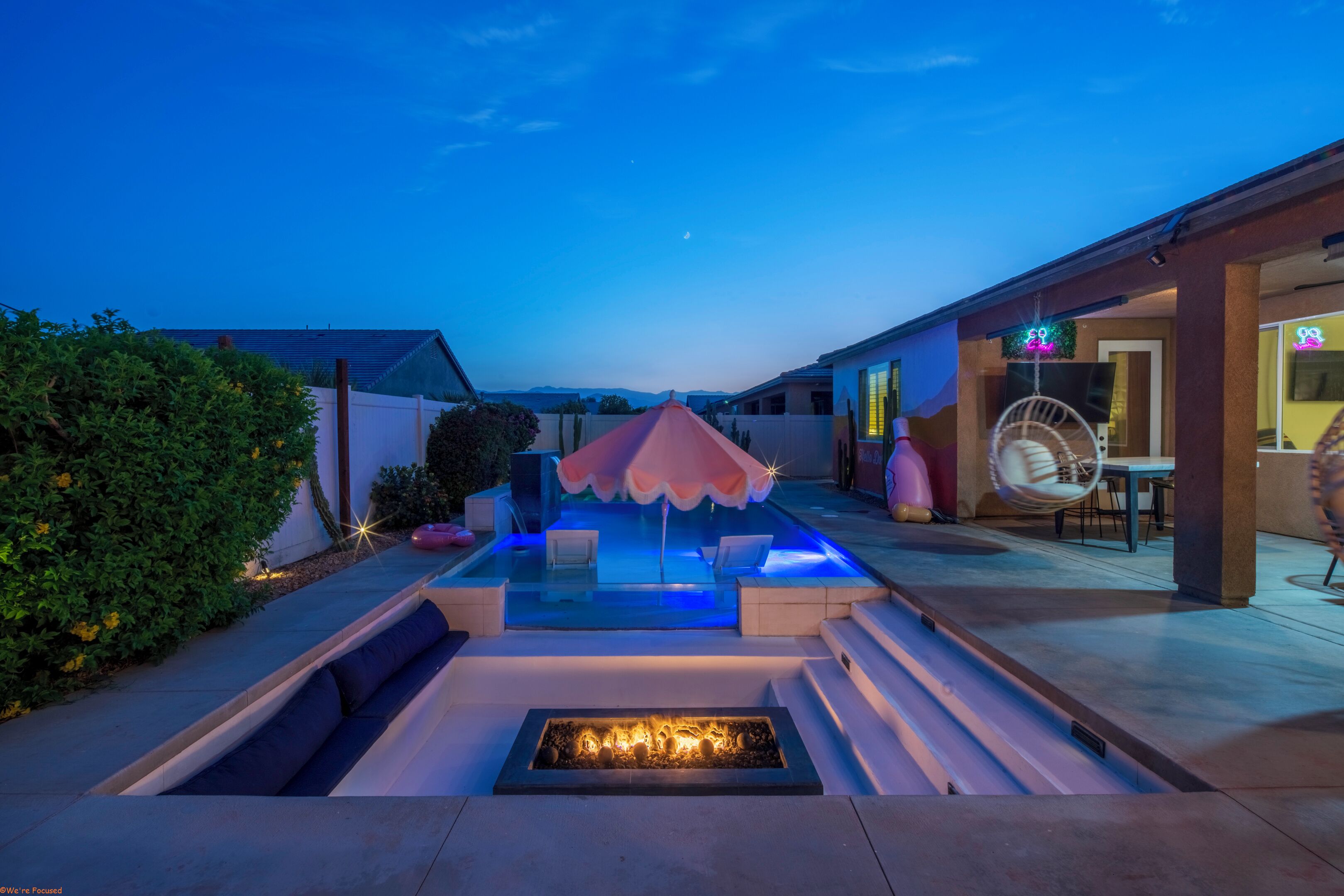 A pool area with a fire feature, seating, and a covered section.