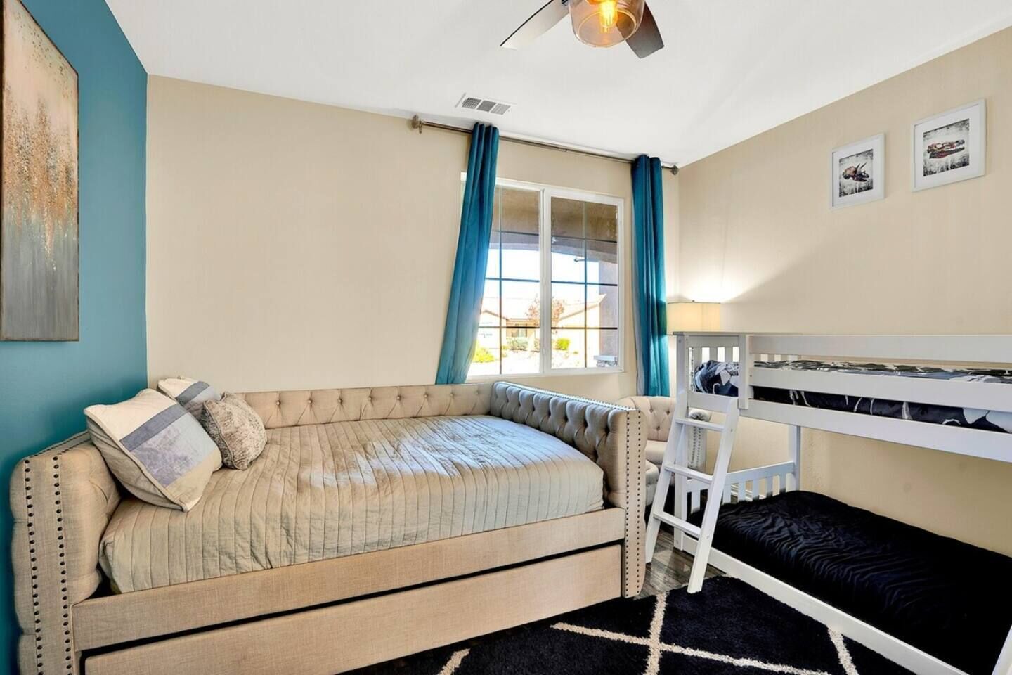A cozy room with a sofa, a bunk bed, a desk, and a window with curtains.