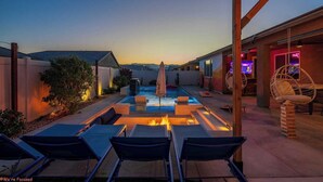 Ein Garten mit Whirlpool, Liegestühlen und einer Pergola.