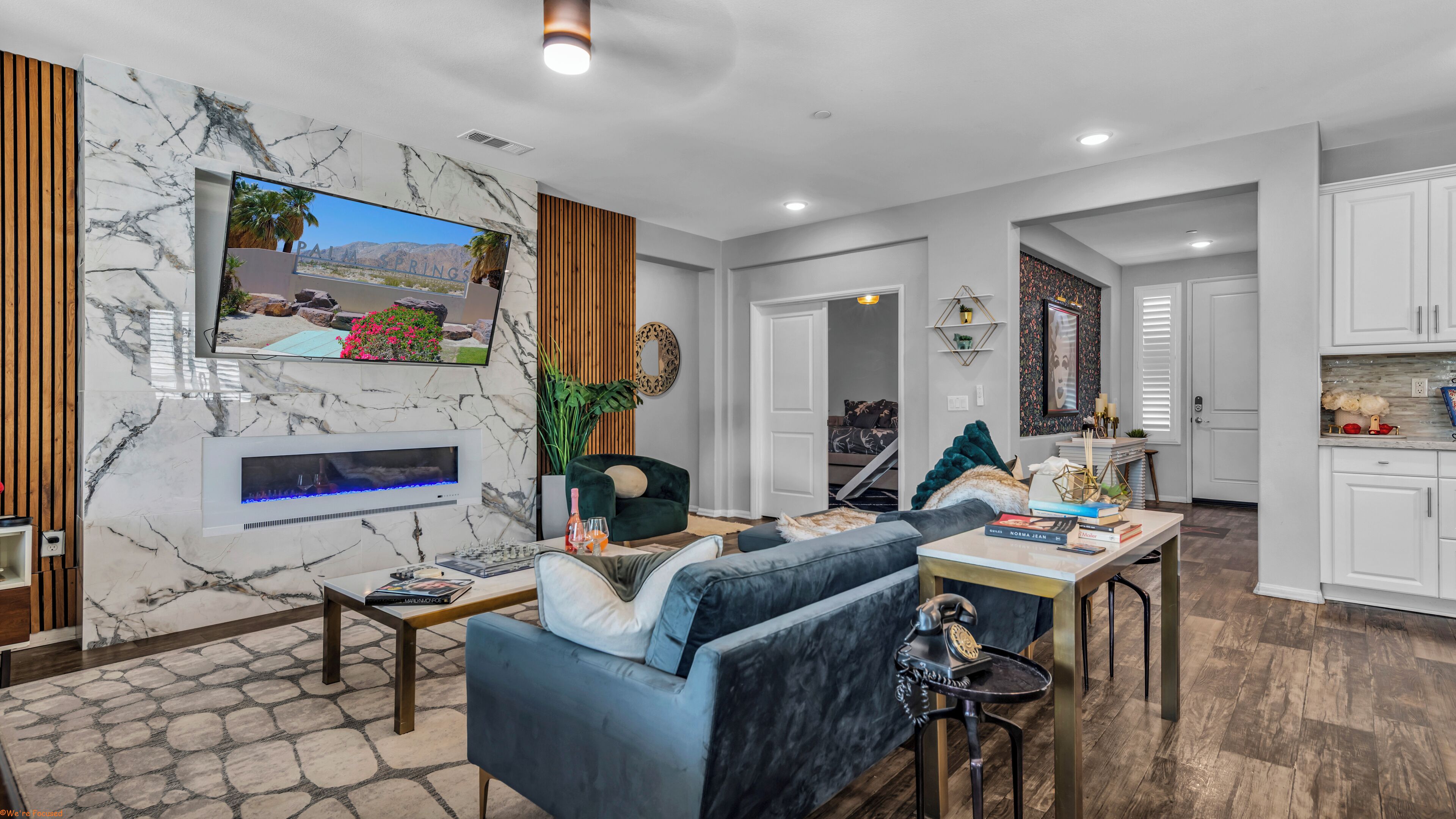 A modern living room with a fireplace, a television mounted on a marble wall, and a cozy seating area.