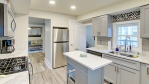 A modern kitchen with a stainless steel refrigerator, a dishwasher, and a marble countertop. - Coastal Comfort & Golfers' Paradise in Sheboygan! (Sheboygan)