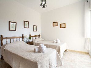 A hotel room with two beds, a nightstand with a lamp, a small potted plant, and framed pictures on the wall. - Wonderful private villa for 10 guests with A/C, private pool, WIFI, TV, terrace and pets allowed (Benissa)