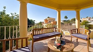 A covered outdoor seating area with two wooden benches and a round table, featuring books and a bottle. - Wonderful private villa for 10 people with private pool, A/C, WIFI, TV, terrace and pets allowed (Benissa)