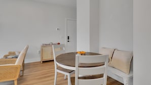 A modern dining area with a round wooden table, white chairs, and a white sofa. - The Bish: Traverse City Fall Getaway | Wine Country & Downtown | Sleeps 2 (Traverse City)