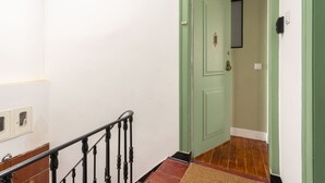 Un escalier avec une rampe en bois menant à une porte verte dotée d’une poignée de porte.