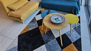 A modern living room with a sofa, a yellow armchair, a coffee table, and pendant lights.
