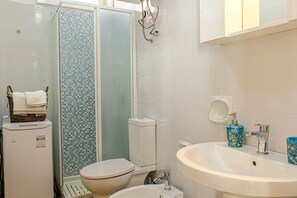 Een badkamer met een toilet, hygiëneschuimer en wastafel.