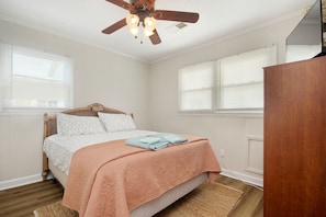 Un dormitorio con cama, ventilador de techo y armario de madera.