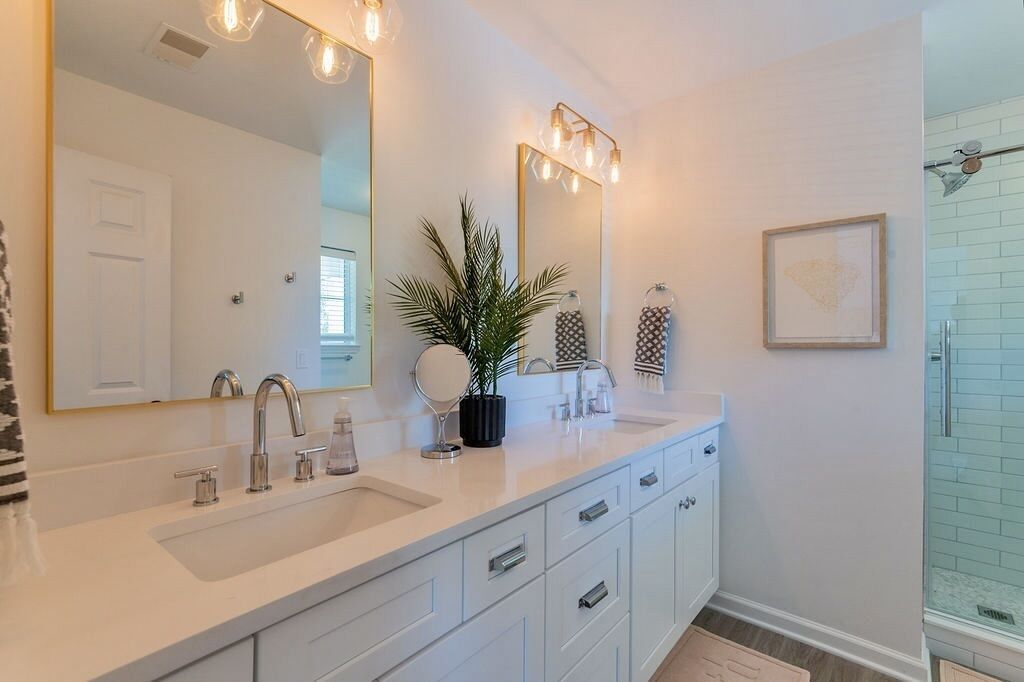 A modern bathroom with a large mirror, two sinks, and a shower area.