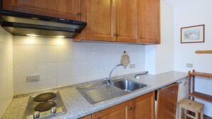 A kitchen with wooden cabinets, a stainless steel sink, a double electric stove, and a granite countertop.