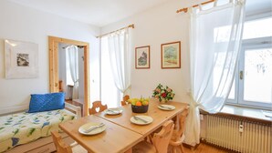 A cozy room with a wooden table set for two, a bed with a floral duvet, and a radiator.