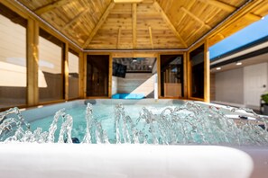 Un intérieur en bois avec un jacuzzi et une vue sur une piscine.