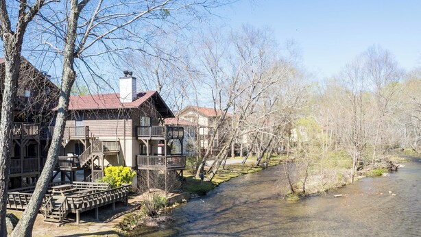 A riverside wooden building with multiple balconies and a clear waterway.