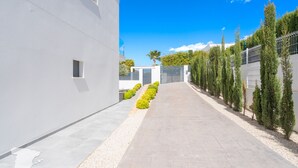 Un bâtiment moderne, doté d’un chemin d’accès épuré et rectiligne menant à une entrée fermée par un portail.