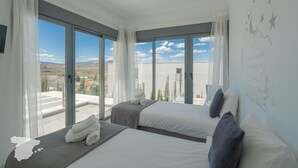 Une chambre d’hôtel avec deux lits, de grandes fenêtres et une vue sur la ville.