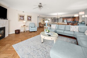 Un salon comprenant un canapé, des fauteuils, une table basse, une cheminée et un ventilateur de plafond.