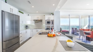 A modern kitchen with a large island, stainless steel appliances, and a view of the ocean. - Sublime 3 bedroom condo Encantame Towers Verano 801 (Puerto Peñasco)
