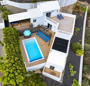 Et moderne hus med swimmingpool, liggestole og en patio.
