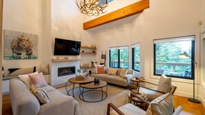Relax in a spacious living room with a fireplace, sofas, and armchairs, offering a view of the surrounding greenery.