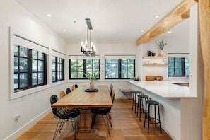 Een moderne keuken met een houten eettafel, zwarte stoelen en een hanglamp.