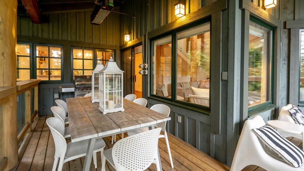 Een houten terras met een tafel, stoelen, een lantaarn en uitzicht op de omgeving.