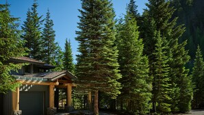 A lodge with a covered entrance, surrounded by tall evergreen trees.
