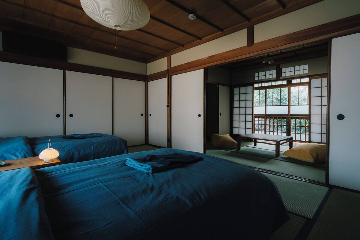 Um quarto japonês tradicional com piso de tatame, portas deslizantes e teto de madeira baixo.