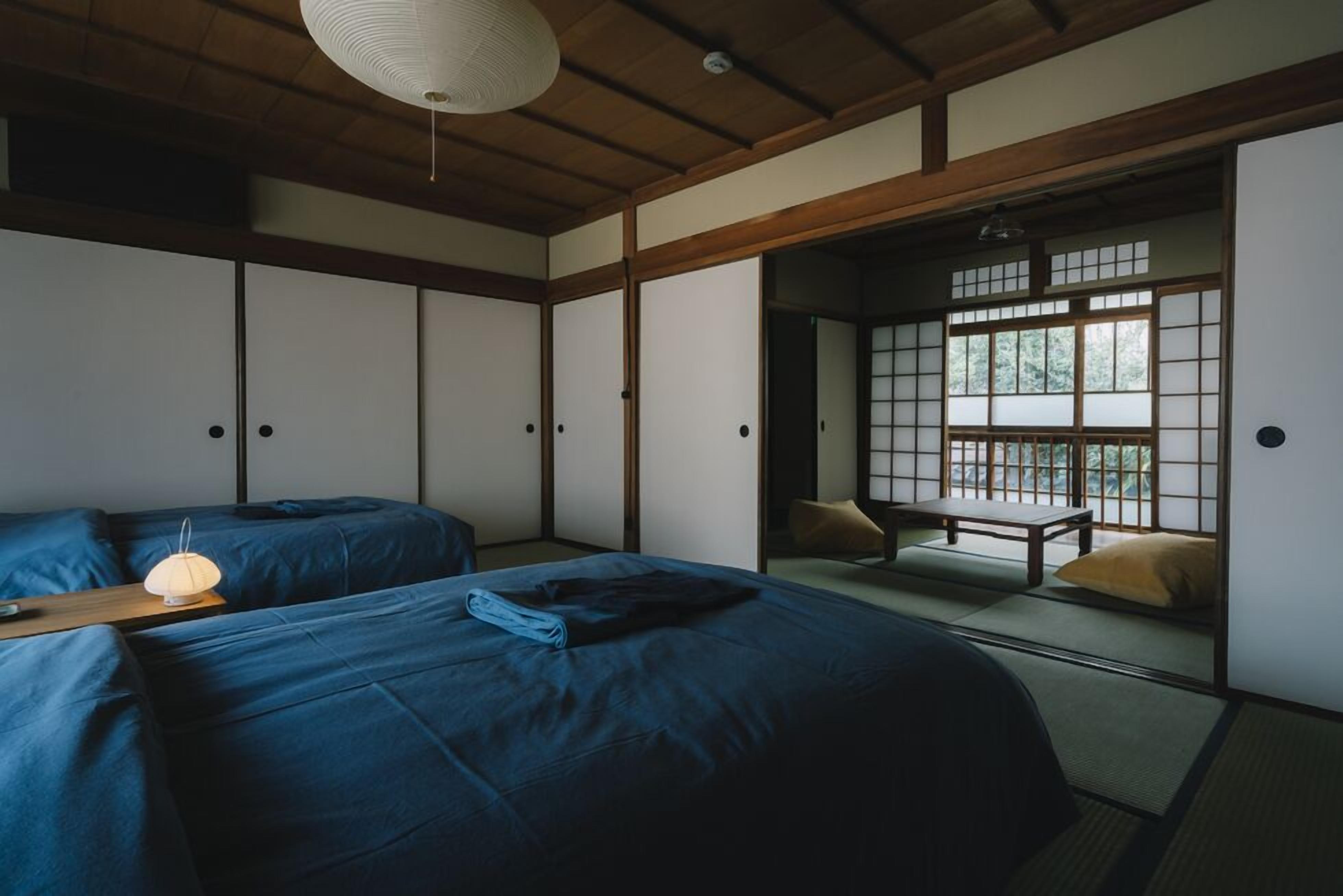 Una habitación japonesa tradicional con suelo de tatami, una mesa baja y puertas correderas.
