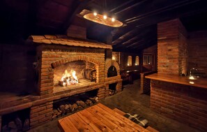 Un intérieur rustique avec une cheminée en briques, des meubles en bois et un plafond en pierre.