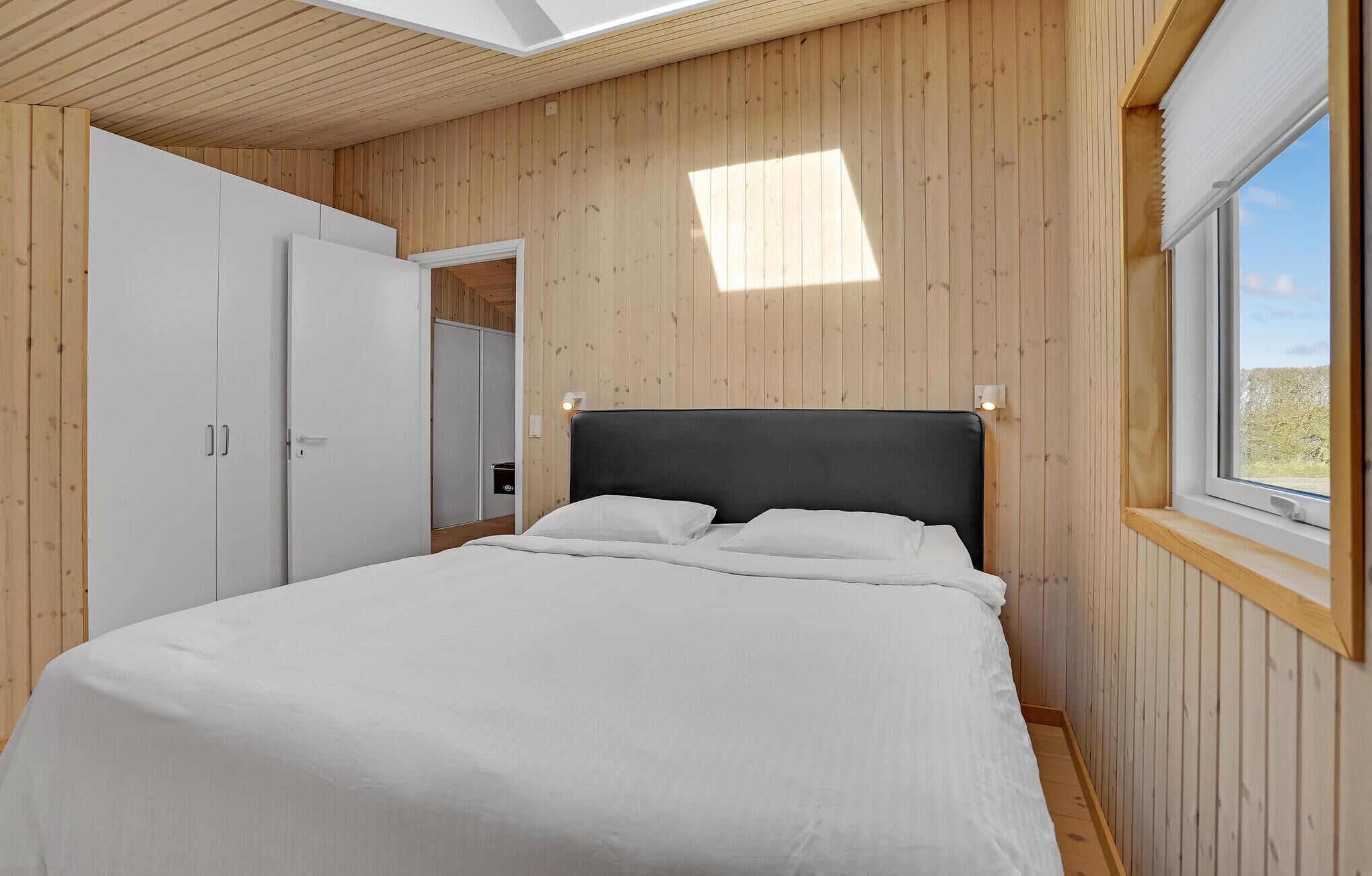 A bedroom with a bed, a wardrobe, and a window.