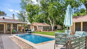 A backyard with a swimming pool, patio furniture, and a covered seating area. - My Little House | Hot Tub | Shared Pool (Fredericksburg)