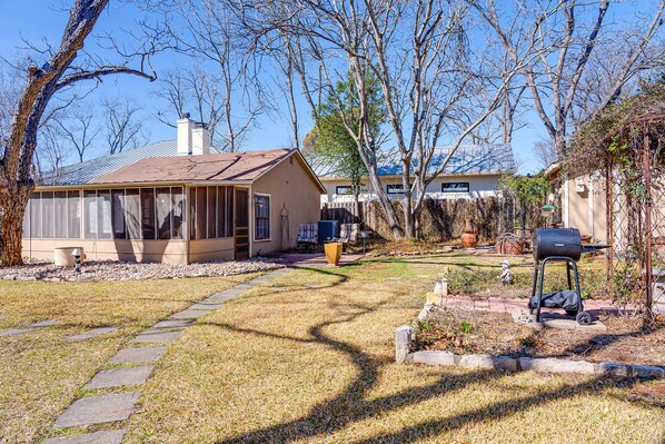 A residential backyard with a house, a barbecue grill, and a garden path.
