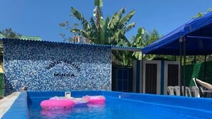 Una piscina con interior azul, rodeada por un muro de azulejos que muestra el texto "HOSTEL MINDanao".
