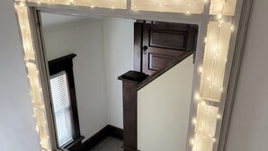Espejo con luces LED en el borde, que refleja una escalera y una puerta.