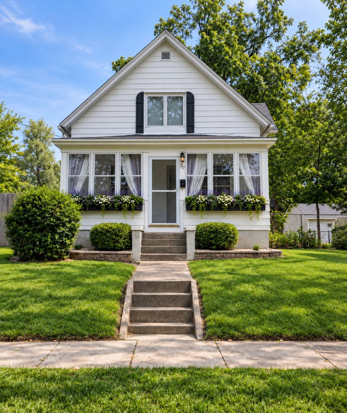 A two-story house with a front porch, a set of stairs leading to the entrance, and a well-maintained lawn.